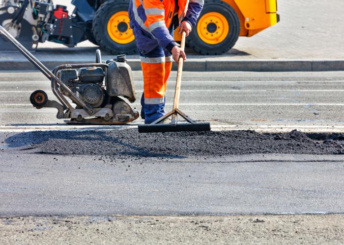Crew spreading hot asphalt during driveway paving Plano project to repair and resurface a residential driveway.